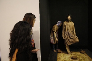 Two female visitors look on as performance artists present their exhibit ‘Rang-e-Khaak’ at “We Are All Mad Here” exhibition